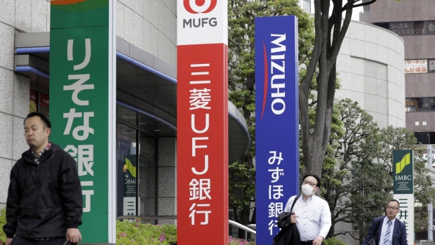 Pedestrians walk past signage for Resona Bank Ltd., from left, MUFG Bank Ltd., Mizuho Bank Ltd. and Sumitomo Mitsui Banking Corp. in Tokyo, Japan, on Friday, May 10, 2019. Japan's mega banks will announce their year-end earnings figures on on May 15.