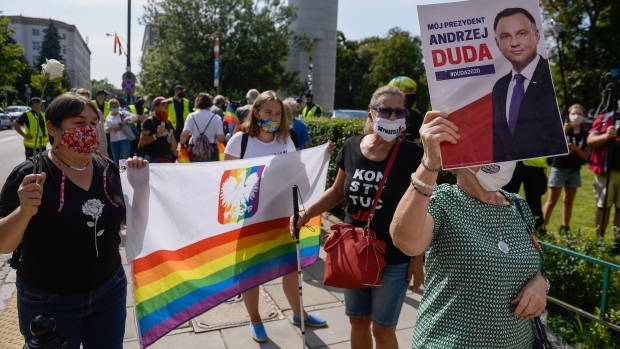 LGBT activists wear protective face masks and hold a rainbow flag with the Polish coat of arms as they protest against Andrzej Duda swearing in ceremony in front of parliament in Warsaw on Aug. 6.