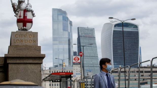 A pedestrian wearing a protective face masks passes a dragon statue, the symbol of the City of London, U.K., on Tuesday, Aug. 4, 2020. The U.K.'s plans to block further spikes in coronavirus allow for ministers to lock down London, U.K. Prime Minister Boris Johnson's spokesman said, as officials prepare for a resurgence of Covid-19 in the months ahead.