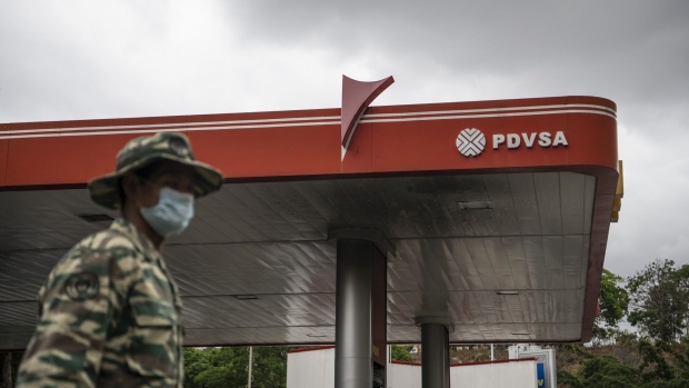 A soldier wearing a protective mask stands guard outside a Petroleos de Venezuela SA gas station in Caracas. Photographer: Carlos Becerra/Bloomberg