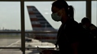 A traveler wearing a protective mask walks past an American Airlines Group Inc. plane tail fin at Ronald Reagan National Airport (DCA) in Arlington, Virginia, U.S., on Tuesday, June 9, 2020