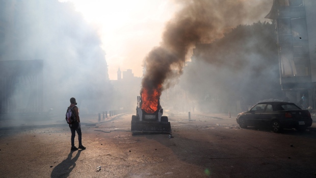A protester stands alongside an excavator on fire during a demonstration close to parliament in Beirut, Lebanon, on Saturday, Aug. 8, 2020. Lebanese protesters took to the streets of Beirut on Saturday amid growing anger at the government following the devastating blast that killed dozens this week.