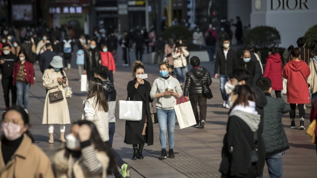 Shoppers and pedestrians wearing protective masks walk past stores on Nanjing Road in Shanghai, China, on Saturday, March 14, 2020. Data on China's industrial output, investment and retail sales due Monday are forecast to show an across-the-board contraction for the first time on record, evidence of the extent to which the coronavirus has ravaged the economy. Photographer: Qilai Shen/Bloomberg