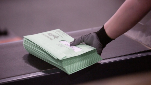 A worker gathers enveloped ballots to place in a postal service bin at the Runbeck Election Services facility in Phoenix, Arizona.