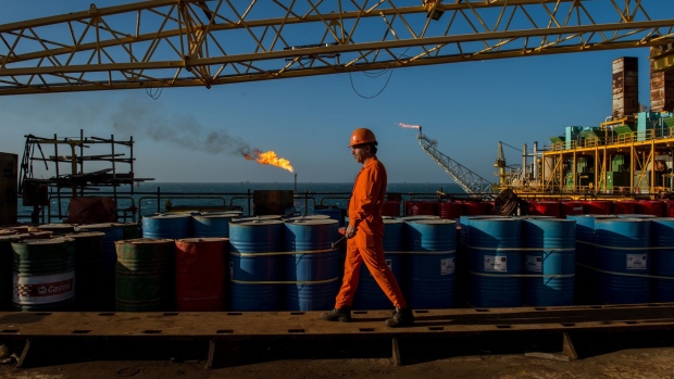 A worker passes stores of oil drums and gas flares while working aboard an offshore oil platform in the Persian Gulf's Salman Oil Field, operated by the National Iranian Offshore Oil Co., near Lavan island, Iran, on Friday, Jan. 6. 2017. Nov. 5 is the day when sweeping U.S. sanctions on Iran’s energy and banking sectors go back into effect after Trump’s decision in May to walk away from the six-nation deal with Iran that suspended them.