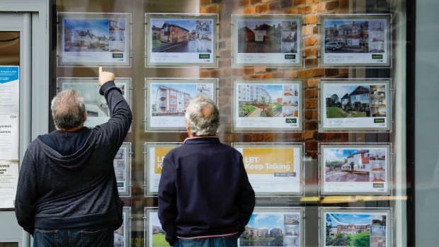 Pedestrians view displays in an estate agent's window in Guildford, U.K., on Friday, June 12, 2020. U.K. house prices fell the most in more than a decade and consumer borrowing plunged as the coronavirus lockdown shuttered the economy.