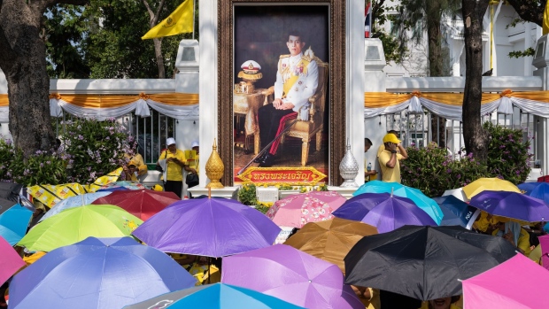 People shelter under umbrellas by an image of King Maha Vajiralongkorn as they await his royal procession in Bangkok, Thailand, on Sunday, May 5, 2019. Vajiralongkorn was crowned on Saturday in a religious ceremony more than two years after ascending to the throne following the death of his father, King Bhumibol Adulyadej. Photographer: Nicolas Axelrod/Bloomberg