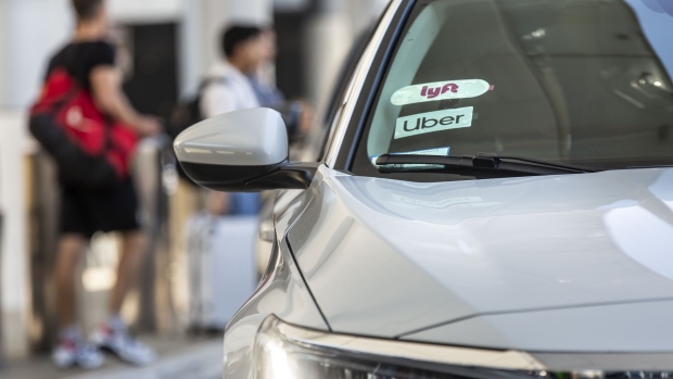 Lyft and Uber badges are displayed on the windshield of a vehicle. Photographer: Allison Zaucha/Bloomberg