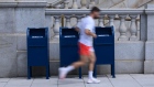 A runner wearing a protective mask walks by United States Postal Service (USPS) collection boxes near Capitol Hill in Washington, D.C., U.S., on Friday, Aug. 14, 2020. President Trump yesterday directly tied his opposition to a proposed $25 billion financial lifeline for the Postal Service to his criticism of efforts to encourage mail-in voting during the coronavirus pandemic. Photographer: Erin Scott/Bloomberg