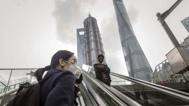 Pedestrians wearing protective masks ride an escalator in the Lujiazui Financial District of Shanghai, China, on Monday, March 2, 2020. The pressure to get China back to work after the coronavirus shutdown is resurrecting an old temptation: doctoring data so it shows senior officials what they want to see. Photographer: Qilai Shen/Bloomberg