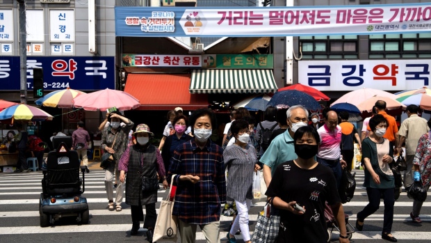 Pedestrians wearing protective masks cross a road in Daejeon, South Korea, on Friday, June 5, 2020. South Korea has refrained from imposing a full lockdown to contain the virus outbreak, instead relying on mass testing and loose social distancing rules.