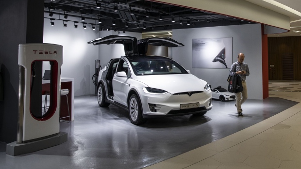 A man walks past a Tesla Model X electric vehicle on display at a showroom in Hong Kong.