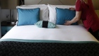 A chambermaid prepares a bed in a guest room 