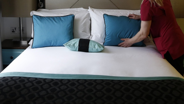 A chambermaid prepares a bed in a guest room 