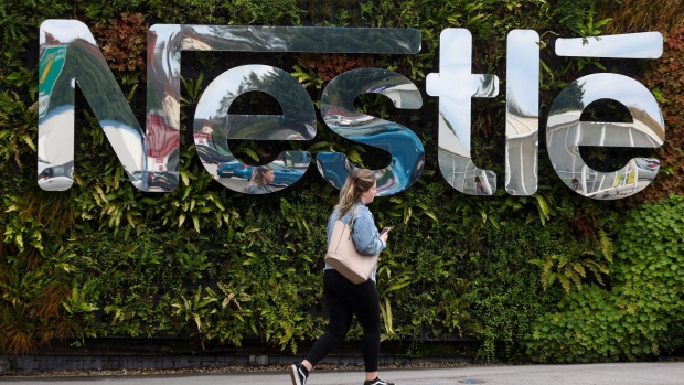 A pedestrian passes a Nestle SA logo at the Nescafe factory, operated by Nestle SA, in Tutbury, U.K., on Thursday, Aug. 23, 2018. European consumer-goods giants ranging from Nestle SA to Anheuser-Busch InBev NV and Diageo Plc are stepping up their response to activist threats by cutting costs, shedding underperforming brands and returning cash to investors. Photographer: Simon Dawson/Bloomberg