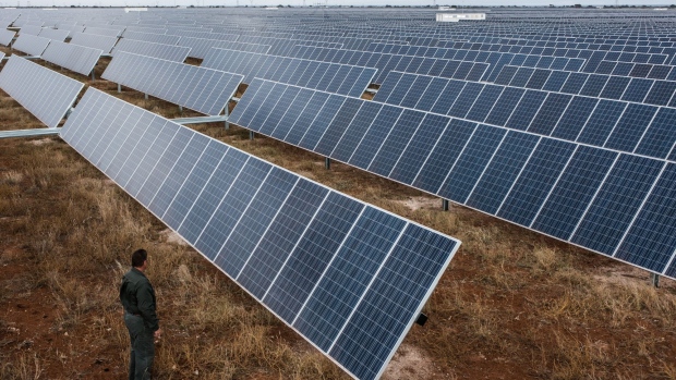 A visitor inspects photovoltaic panels operating in the Sishen solar park, operated by Acciona SA, in Kathu, Northern Cape, South Africa, on Tuesday, June 2, 2015. South Africa, which has implemented rolling blackouts this year as electricity demand exceeds supply, is running a five-round program of tenders to tap new sources of energy and encourage more private companies to build power projects. Photographer: Bloomberg/Bloomberg