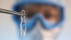 A worker wearing personal protective equipment (PPE) uses tweezers to pick up an ampoule containing a component of the 'Gam-COVID-Vac' COVID-19 vaccine