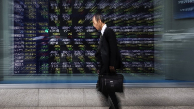 A pedestrian walks past an electronic stock board outside a securities firm in Tokyo, Japan, on Friday, April 26, 2019. Japan's retail investors have propelled their net long yen positions against the dollar to near a record ahead of the nation's extended Golden Week holidays. Photographer: Keith Bedford/Bloomberg