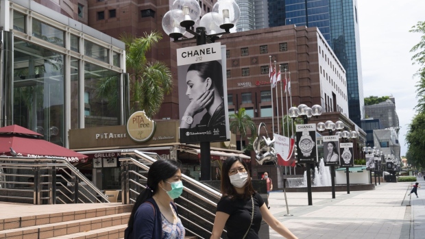 Pedestrians wearing protective masks exit Ngee Ann City shopping and commercial center on Orchard Road in Singapore, on Saturday, July 25, 2020. Singapore’s economy plunged into recession last quarter as an extended lockdown shuttered businesses and decimated retail spending, a sign of the pain the pandemic is wreaking across export-reliant Asian nations.