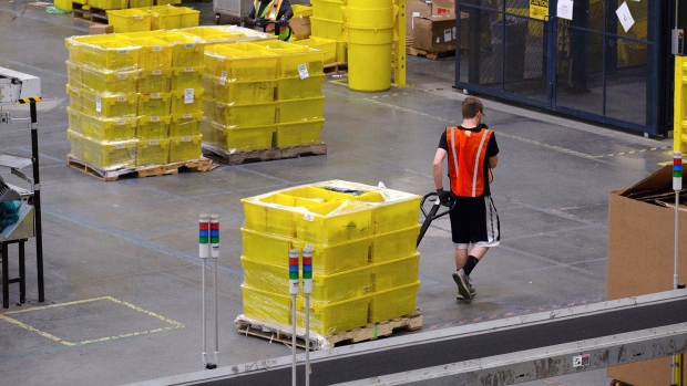 An employee pulls a pallet jack carrying plastic crates containing online orders at the Amazon.com Inc. fulfillment center in Robbinsville, New Jersey. Photographer: Bess Adler/Bloomberg
