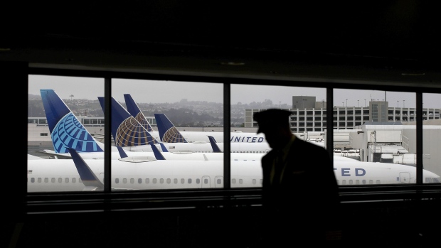 SAN FRANCISCO, CALIFORNIA - APRIL 12: A pilot walks by United Airlines planes as they sit parked at gates at San Francisco International Airport on April 12, 2020 in San Francisco, California. San Francisco International Airport has a seen a huge decline in daily flights since the coronavirus shelter in place. United Airlines, the airport's largest carrier with the most daily flights with 290 flights per day before the start of the COVID-19 pandemic, has reduced their daily flights to 50 per day. (Photo by Justin Sullivan/Getty Images) Photographer: Justin Sullivan/Getty Images