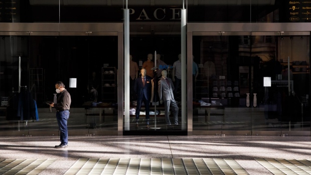 A pedestrian wearing a protective mask stands in front of a closed store at Brookfield Place in the financial district of Toronto, Ontario, Canada, on Friday, May 22, 2020.