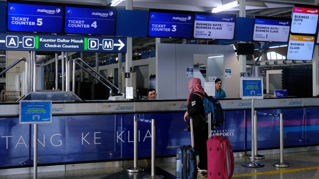 A traveler is assisted at a ticket counter for Malaysia Airlines Bhd. at Kuala Lumpur International Airport (KLIA) in Sepang, Selangor, Malaysia. on Friday, June 12, 2020. Malaysia further eased restrictions on people's movement, allowing most activities including domestic tourism to resume on June 10, after letting nearly all sectors of the economy to reopen in early May. Photographer: Samsul Said/Bloomberg