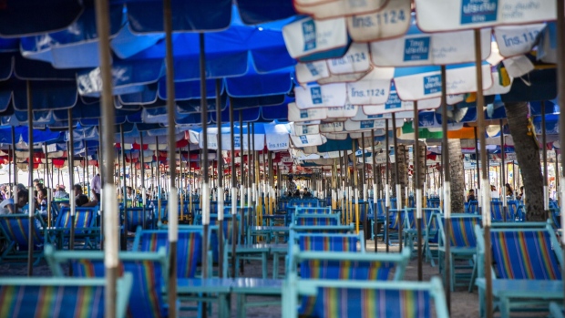 Visitors observe social distancing regulations while sitting on beach chairs under umbrellas at Bangsaen Beach in Chonburi, Thailand, on Sunday, June 14, 2020. Thailand said a number of countries, including China and Japan, are interested in discussions about travel bubbles, as the nation considers protocols for the eventual return of foreign tourists. Local tourism has already restarted. Photographer: Andre Malerba/Bloomberg