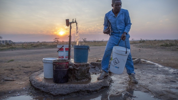 A local resident fills buckets and containers with water at a communal tap as the sun sets in Empompini in Cowdray Park, Bulawayo, Zimbabwe, on Saturday, Aug. 3, 2019. Zimbabwe is in the grip of a nationwide drought that’s depleted dams, cut output by hydropower plants, caused harvests to fail and prompted the government to appeal for $464 million in aid to stave off famine.