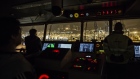 Crew members look out from the control room of a container ship as the vessel prepares to dock at the Kwai Tsing Container Terminal.