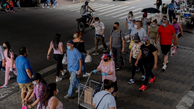 Pedestrians wearing protective masks cross a street in Queens, New York, on June 27. Photographer: Amir Hamja/Bloomberg