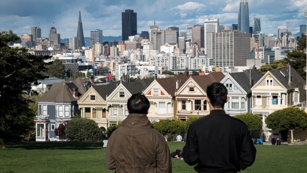 People stand in Alamo Square overlooking the city skyline in San Francisco, California, U.S., on Thursday, March 26, 2020. 