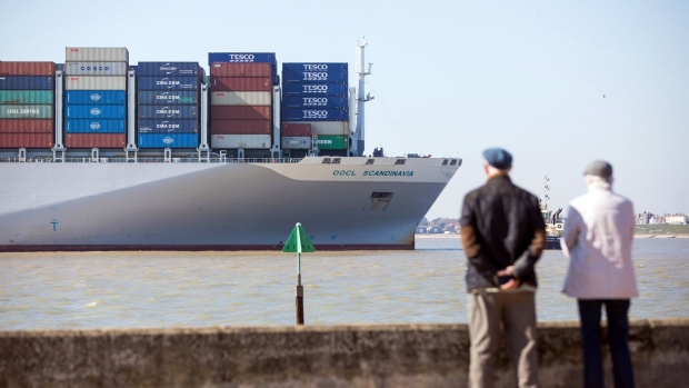 Pedestrians watch as the Scandinavia container ship, operated by Orient Overseas Container Line Ltd. (OOCL), approaches the dockside at the Port of Felixstowe Ltd., a subsidiary of CK Hutchison Holdings Ltd., in Felixstowe, U.K., on Wednesday, March 25, 2020. Legislation is being introduced by the U.K. Government that might close some ports in the event that there are insufficient border-force officers to maintain adequate border security. Photographer: Chris Ratcliffe/Bloomberg