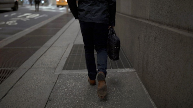 A pedestrian walks along a street near the New York Stock Exchange. Photographer: Jordan Sirek/Bloomberg