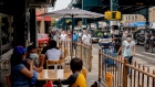 Pedestrians pass in front of customers sitting outside at a restaurant in in the Queens borough of New York.