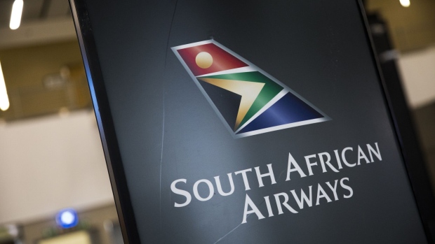 The South African Airways (SAA) logo is displayed on a board at the check-in area inside O.R. Tambo International Airport in Johannesburg, South Africa, on Friday, Feb. 28, 2020. Health experts have voiced concerns over the possible spread of the coronavirus in African nations that may be ill-equipped to handle such a crisis. Photographer: Guillem Sartorio/Bloomberg