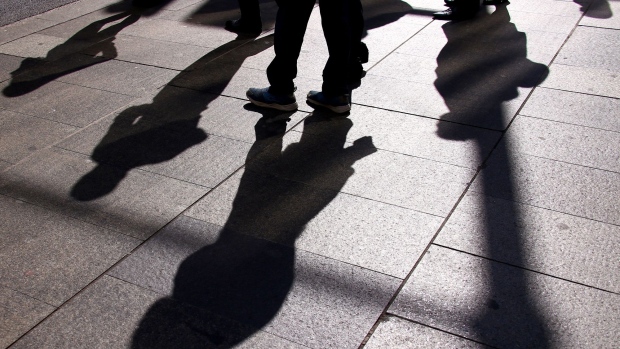 Pedestrians cast shadows on the ground as they walk in the central business district of Sydney, Australia, on Wednesday, May 15, 2019. Australia's economy has been weighed down by a retrenchment in household spending as property prices slump and slash personal wealth. An election Saturday is likely to see the opposition Labor party win power and lift spending further. Photographer: David Gray/Bloomberg
