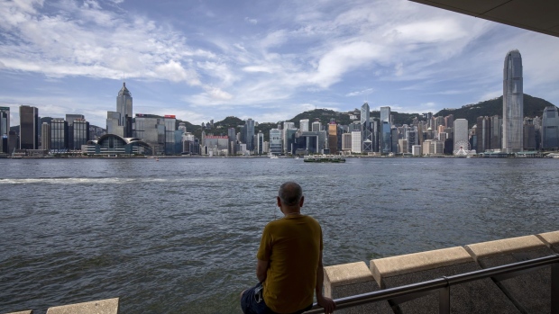 A man sits by the Tsim Sha Tsui waterfront as buildings forming the city skyline stand across the harbor in Hong Kong, China, on Monday, June 29, 2020. The national security law that China could impose on Hong Kong as early as this week won't need to be used if the financial hub's residents avoid crossing certain "red lines," according to Bernard Chan, a top adviser to Hong Kong Chief Executive Carrie Lam. Photographer: Paul Yeung/Bloomberg