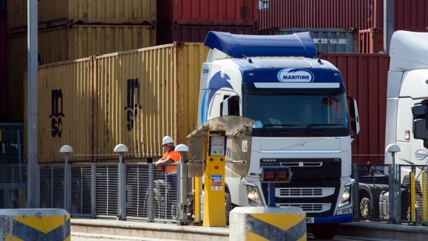 An employee stands next to a truck carrying a shipping container on the dockside at London Gateway port, operated by DP World Plc, in Stanford-le-Hope, U.K., on Tuesday, Sept. 22, 2020. France said the European Union should keep pursuing a free-trade agreement with the U.K. while warning that any British violation of the Brexit agreement would end the push.