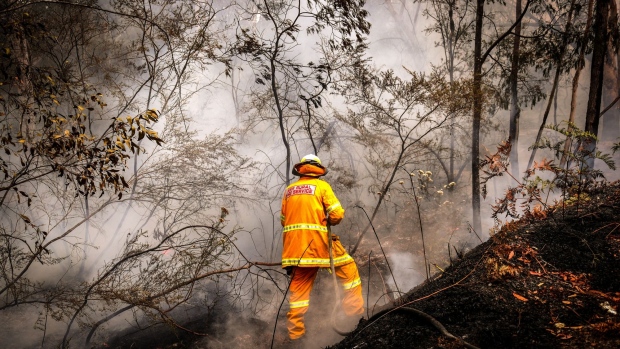 A New South Wales Rural Fire Service volunteer douses a fire during back-burning operations near the town of Kulnura, Australia.