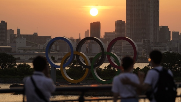 The sun sets behind the Olympic rings floating in the waters off Odaiba island in Tokyo. Photographer: Toru Hanai/Bloomberg
