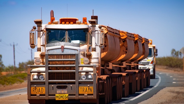 Road trains travel along a highway near Port Hedland, Australia, on Monday, March 18, 2019. A two-day drive from the nearest big city, Perth, Port Hedland is the nexus of Australia’s iron-ore industry, the terminus of one of Australia’s longest private railways that hauls ore about 400 kilometers (250 miles) from the mines of BHP Group and Fortescue Metals Group Ltd. The line ran a record-breaking test train weighing almost 100,000 tons that was more than 7 kilometers long in 2001, and even normal trains haul up to 250 wagons of ore. Photographer: Ian Waldie/Bloomberg