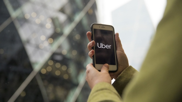 A commuter uses the Uber Technologies Inc. app on a smartphone in view of 30 St Mary Axe also known as 'the Gherkin' in this arranged photograph in London, U.K., on Monday, Nov. 25, 2019. Uber lost its license in London for the second time in less than three years, putting one of its biggest markets outside of the U.S. at risk after the transport regulator said it failed to address safety concerns.