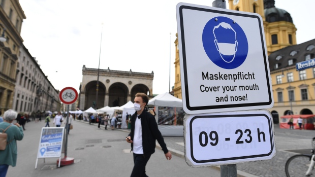 A sign alerts visitors to cover their mouth and nose with face masks in Odeonsplatz square in Munich, Germany in Munich, Germany, on Thursday, Sept. 24, 2020. 