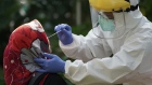 A healthcare worker dressed in personal protective equipment collects a swab sample from a resident at a mobile Covid-19 testing facility in Jakarta, Indonesia, on Wednesday, July 29, 2020. Total coronavirus infections in Indonesia surged past 100,000 amid an easing of physical-distancing rules to allow economic activity to resume, prompting President Joko Widodo to order health officials to focus on containing the disease in the nation's eight main provinces. Photographer: Dimas Ardian/Bloomberg