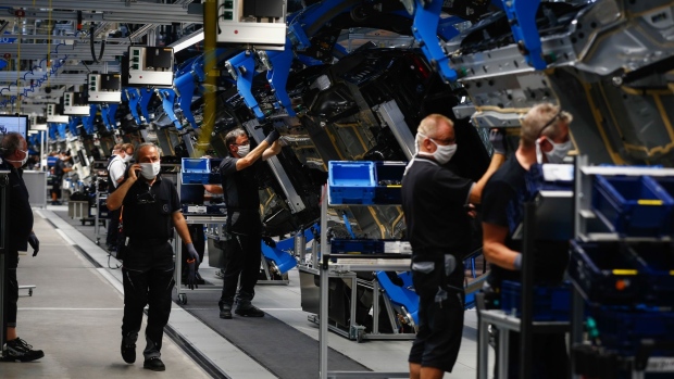 Employees wearing protective face masks inspect the undersides of Mercedes S-Class luxury sedans on the assembly line at the Mercedes-Benz AG Factory 56, operated by Daimler AG, in Sindelfingen, Germany, on Wednesday, Sept. 2, 2020. The latest iteration of the Mercedes S-Class, which the German carmaker presents on Wednesday, will try to please tastes old and new -- offering not just the high-powered combustion variant but also an improved hybrid version and, for the first time, a sleek all-electric sibling sold from next year.