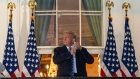 U.S. President Donald Trump removes his protective mask on the Truman Balcony of the White House in Washington, D.C., U.S., on Monday, Oct. 5, 2020. 