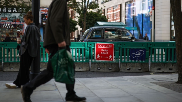 Pedestrians pass a sign that reads "Covid-19 Keep Apart", on Oxford Street in central London, U.K., on Thursday, Oct. 1, 2020. The City of London's traffic-lite streets look set to outlast the pandemic. Photographer: Simon Dawson/Bloomberg