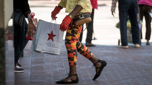 A person wearing protective gloves carries a Macy's Inc. shopping bag while walking on Market Street in San Francisco, California, U.S., on Thursday, Aug. 6, 2020. U.S. consumer sentiment extended its slide in late July as the resurgent coronavirus led to renewed business closings and layoffs, adding to signs the economic recovery is stalling.