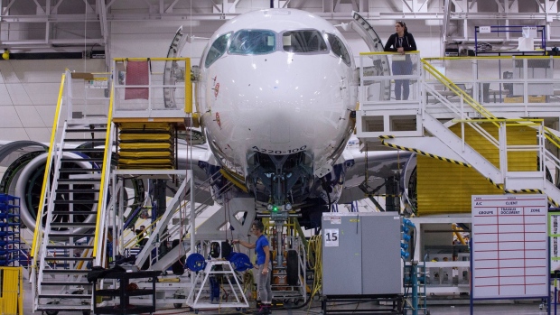 Workers inspect an Airbus SE A220 plane at the end of the assembly line at the Airbus Canada LP assembly and finishing site in Mirabel, Quebec, Canada, on Thursday, Feb. 20, 2020. Airbus CEO Guillaume Faury said that the company plans to invest up to 1 billion euros on the A220 this year. Photographer: Valerian Mazataud/Bloomberg